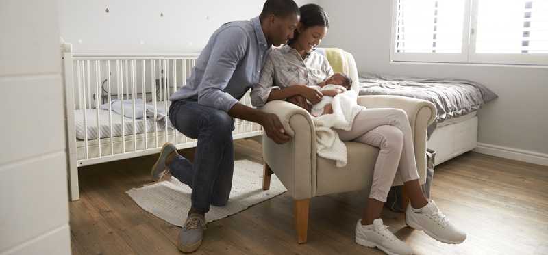 Parents hold a newborn in a nursery.