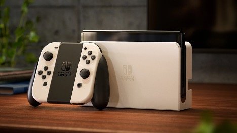 A staged photo of the Nintendo Switch gaming console on a brown table.
