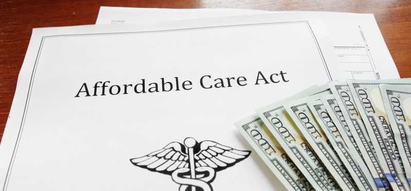 Document titled Affordable Care Act with $100 bills resting on top.