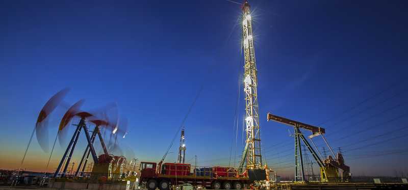 Oil pumps working in the background near a drilling rig.