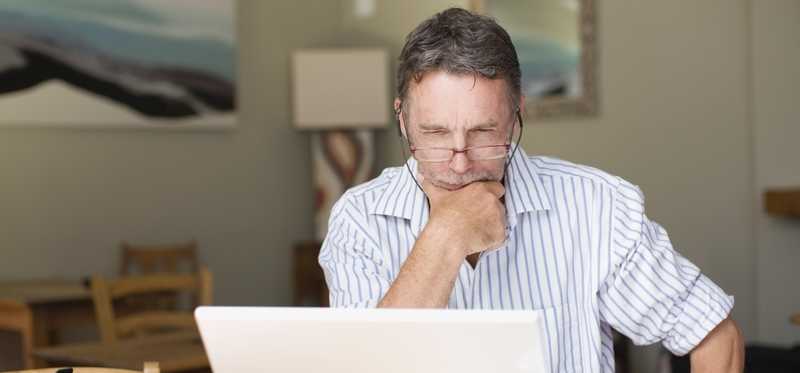 Person looking at a laptop and thinking.