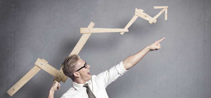 Man pointing up with upward arrow made of wooden planks in the background