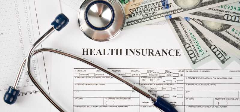 Health insurance document, stethoscope, and bills.