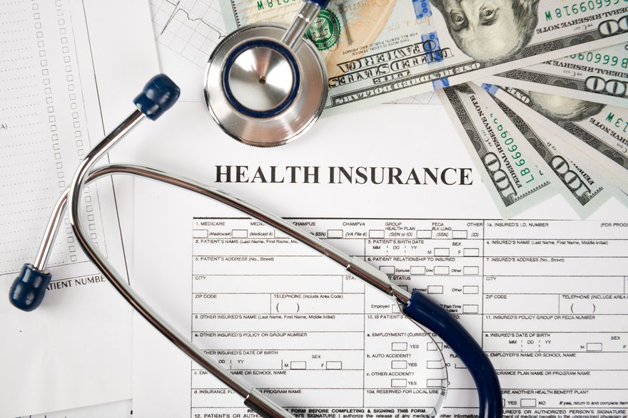 Health insurance document, stethoscope, and bills.