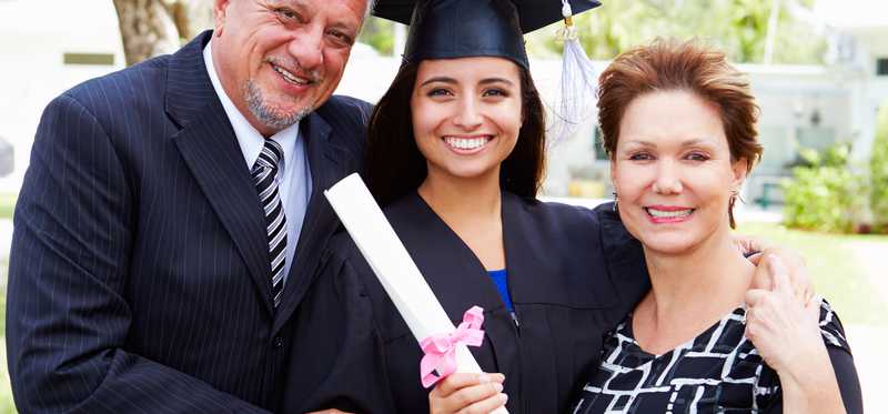 Parents with female college student at graduation in cap and gown.