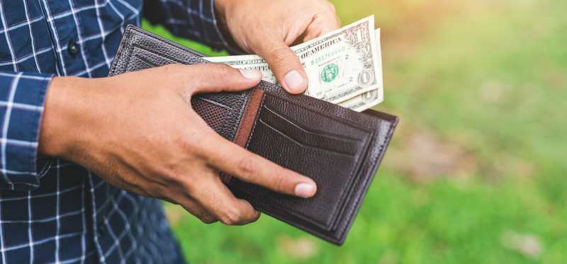Person pulling some cash from a leather wallet.