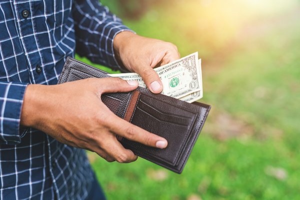 Person pulling some cash from a leather wallet.