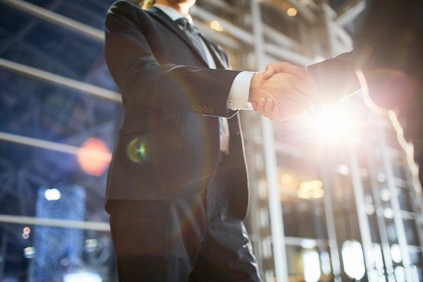 People shaking hands outside of a building.