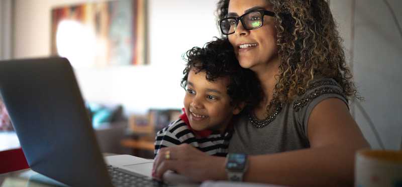 Person at home with child looking at laptop.