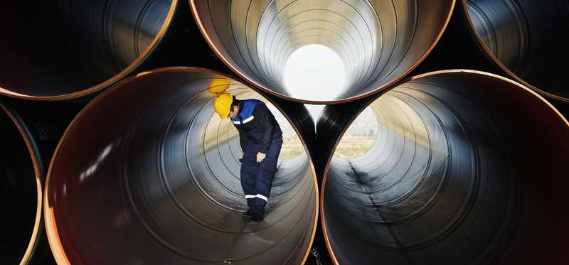 A person inside one of a pile of very large pipes.