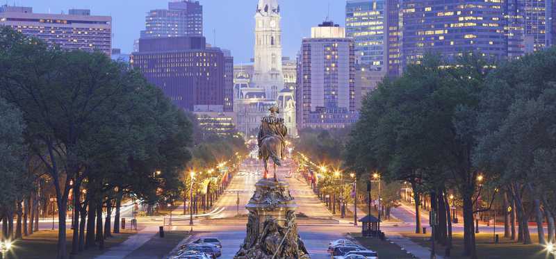 Shot of downtown Philadelphia looking over the back of a statue of a person on a horse.