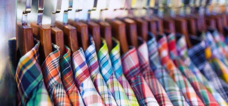Colorful plaid shirts on a department store rack.