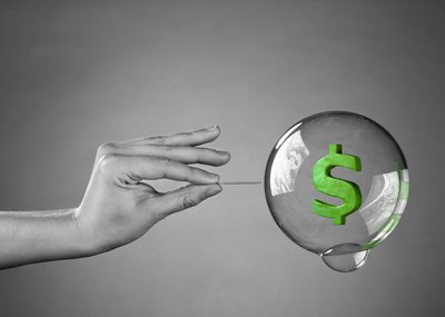 A hand extending to pop a bubble with a green dollar sign floating inside it.