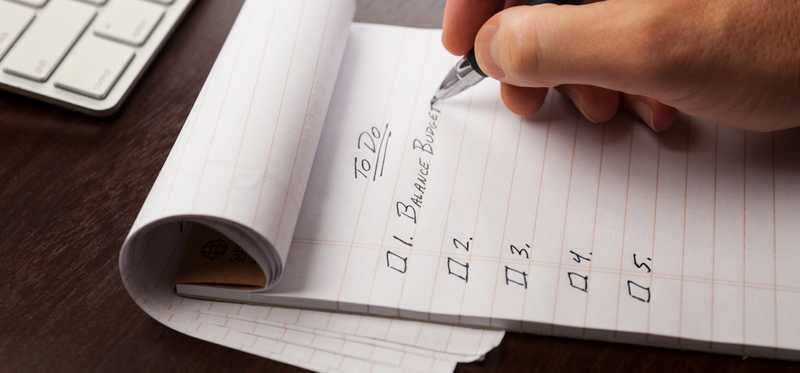Hand writing To Do list in notebook starting with Balance Budget.