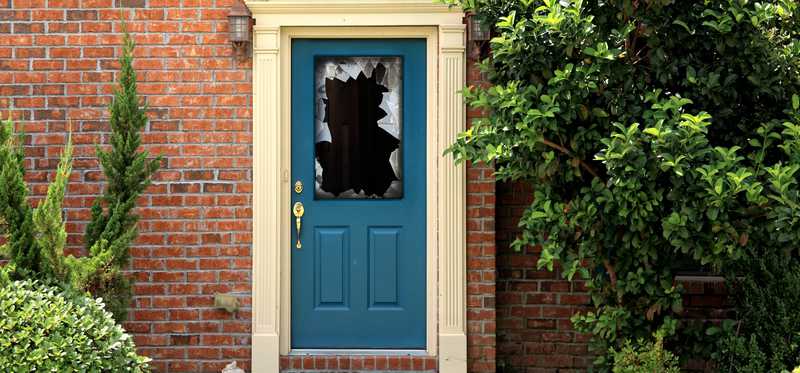 A blue front door with a broken window on it.