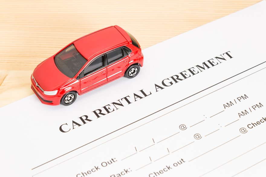 A rental car agreement with red model car on top.
