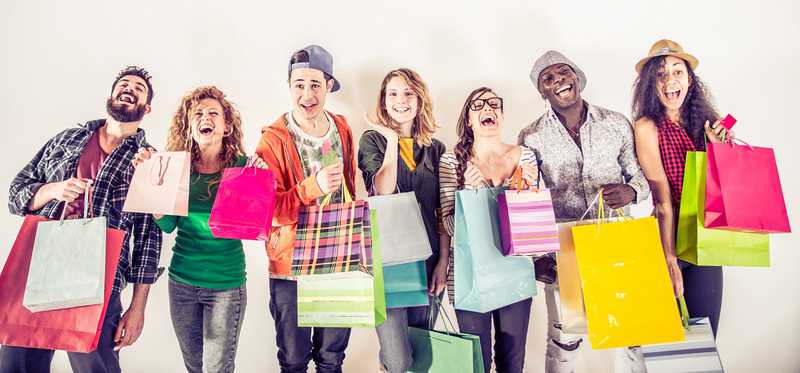 A line of people holding shopping gift bags and looking happy.