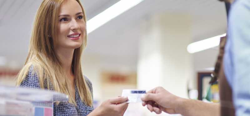 A person hands a credit card to a clerk in a store.