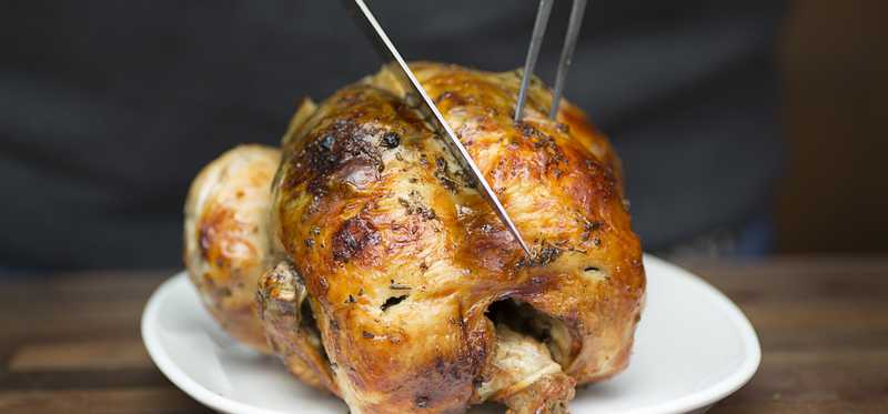 A rotisserie chicken is seen on a plate.