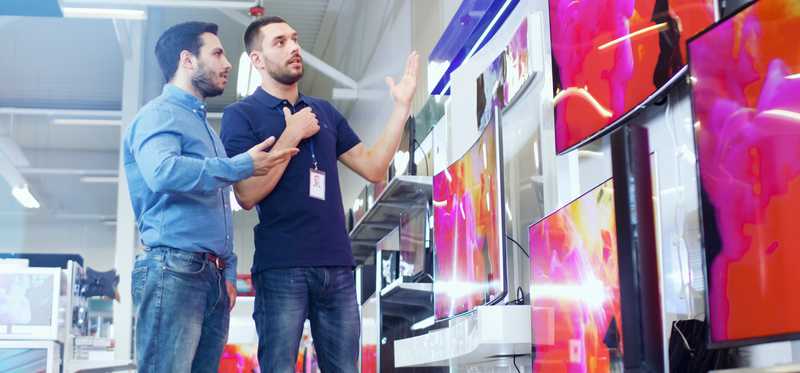 Sales associate and customer look at TVs.