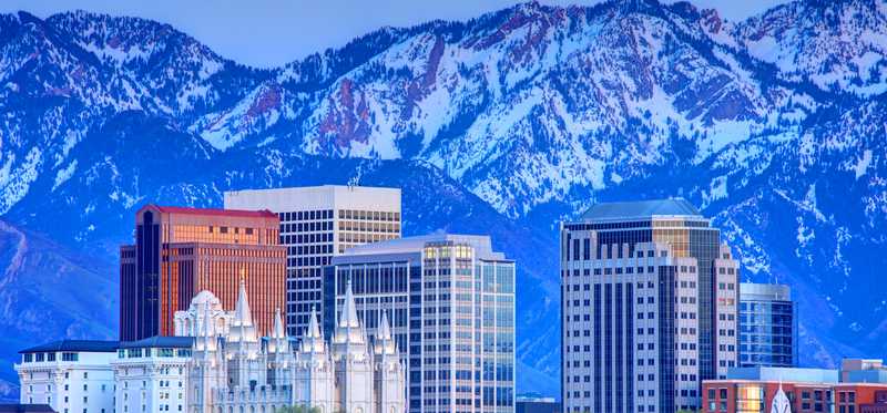 A view of the Salt Lake City skyline that includes the Mormon Cathedral and mountains.