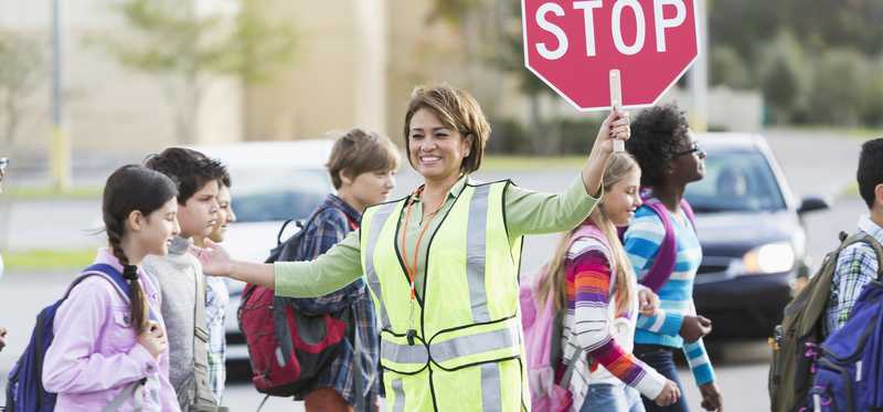 School crossing guard helping young people cross the street.