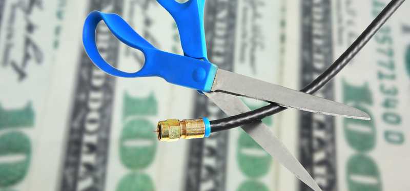 Scissors cutting cable with money in the background.