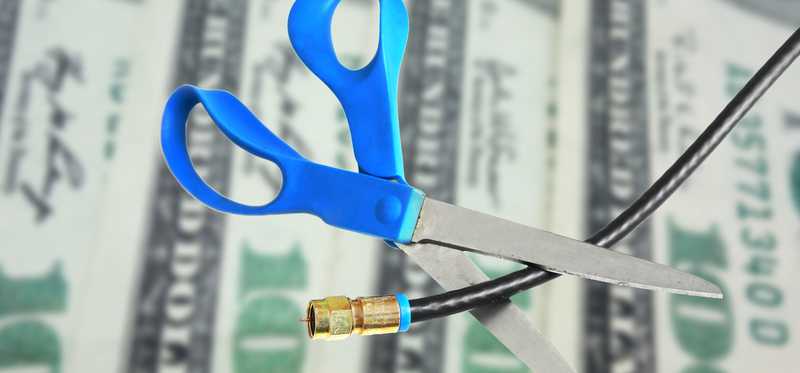 Scissors cutting cable with money in the background.