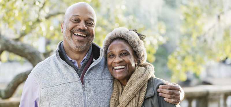 Two people smiling together outside.