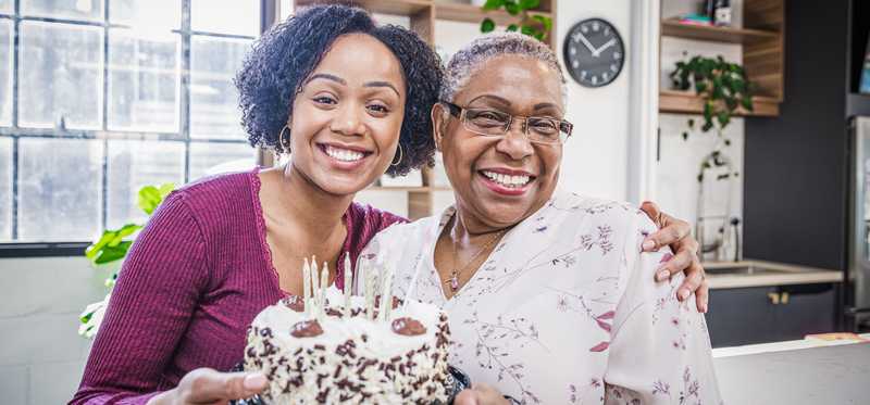 Two people holding a birthday cake and smiling.