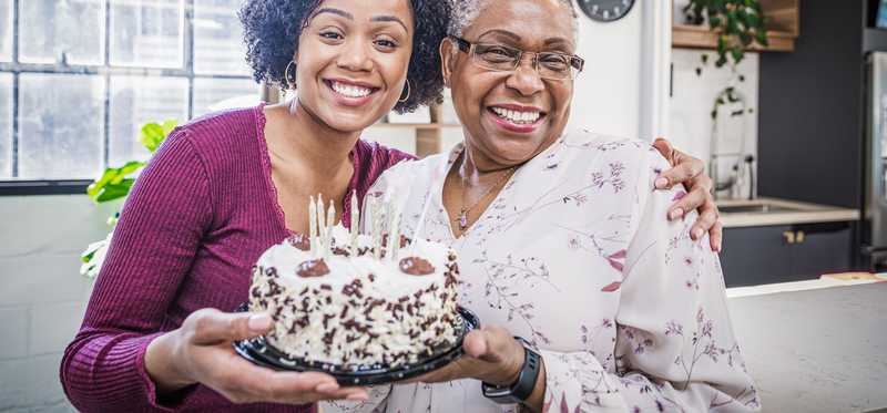 Two people holding a birthday cake and smiling.