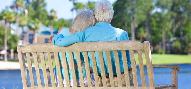 Couple sitting together on a bench overlooking a pond.