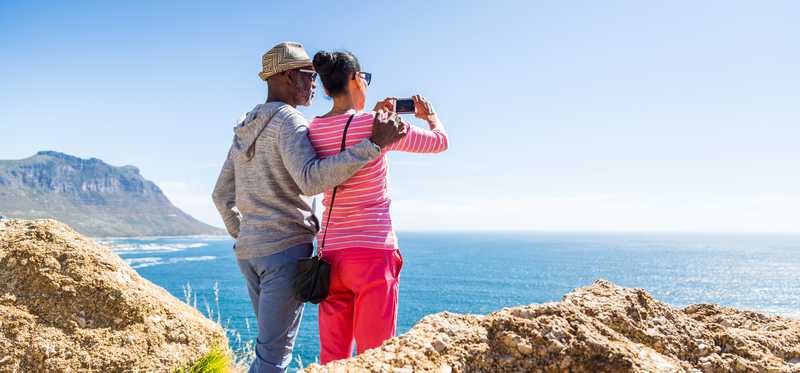 Two people taking photo of the ocean.