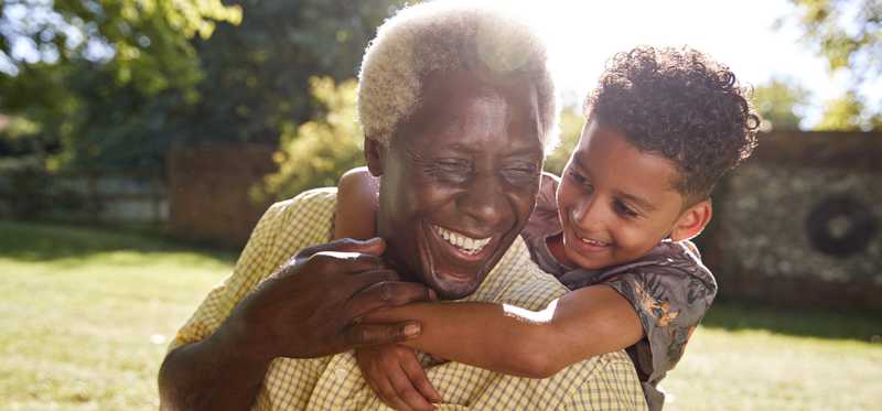 Smiling child hugging an adult outdoors.