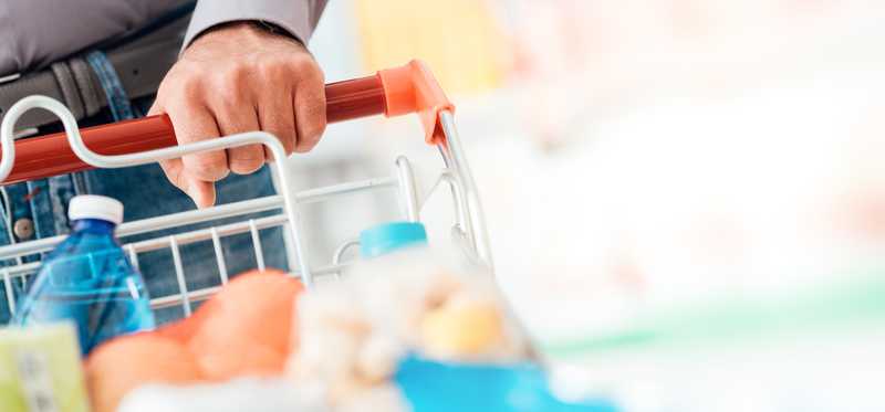 Man pushing a shopping cart with items inside.