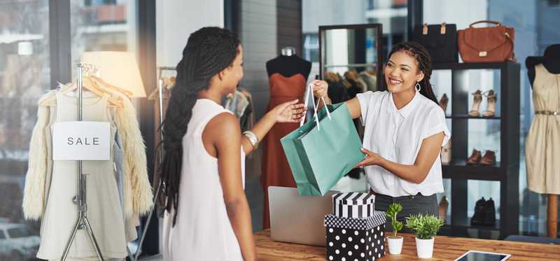 Cashier hands bag to customer at checkout counter.