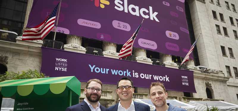 Slack CTO, CFO, and CEO in front of the New York Stock Exchange with a banner announcing the company's IPO.