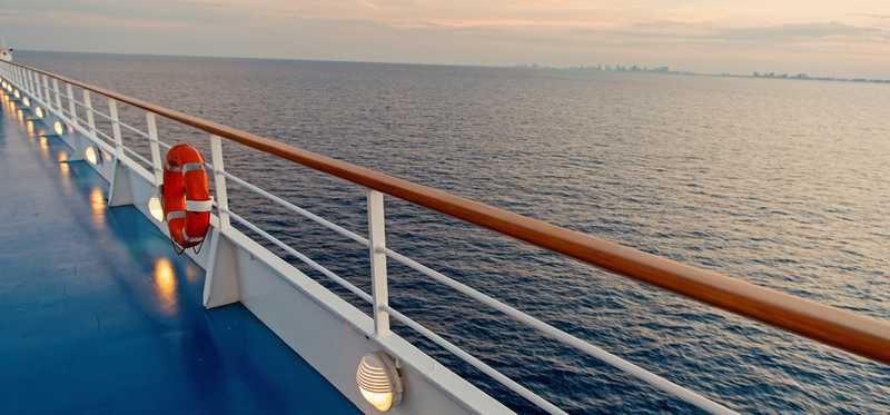 Deck of cruise liner out on the ocean with orange buoy hanging near rails