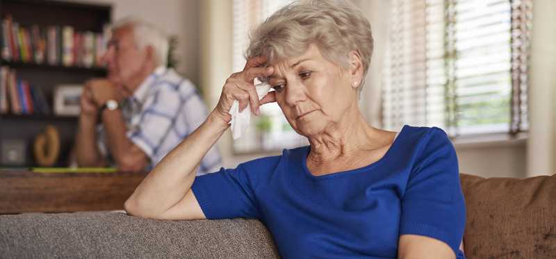 Two people sitting apart and looking stressed.