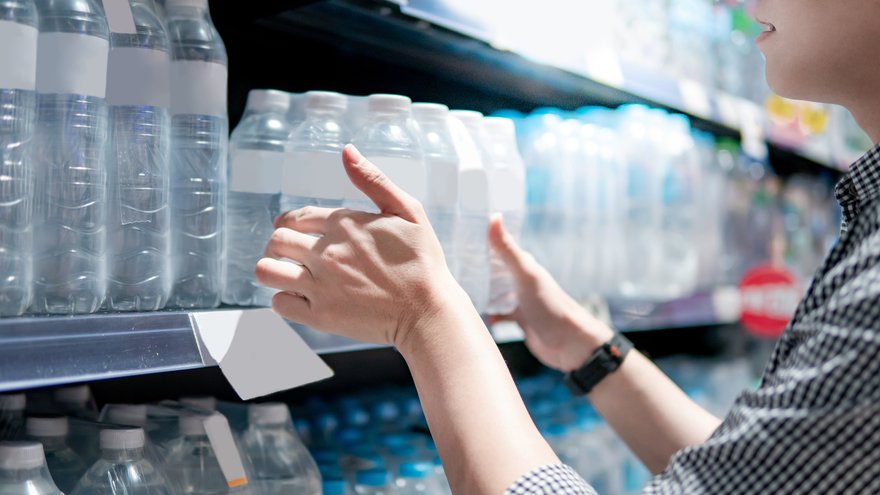 Shopper taking pack of plastic water bottles off shelf