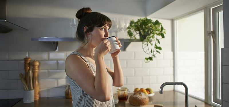 Woman sipping coffee in the early morning and looking out the window