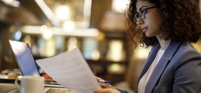 Person sitting at computer while reviewing financial statements.