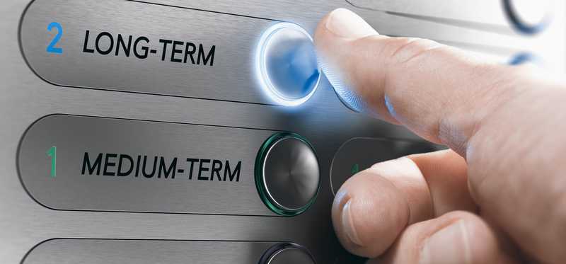 Thumb pressing an elevator button that says long-term.