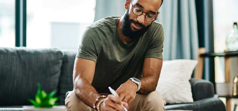 Person sitting on a couch writing.