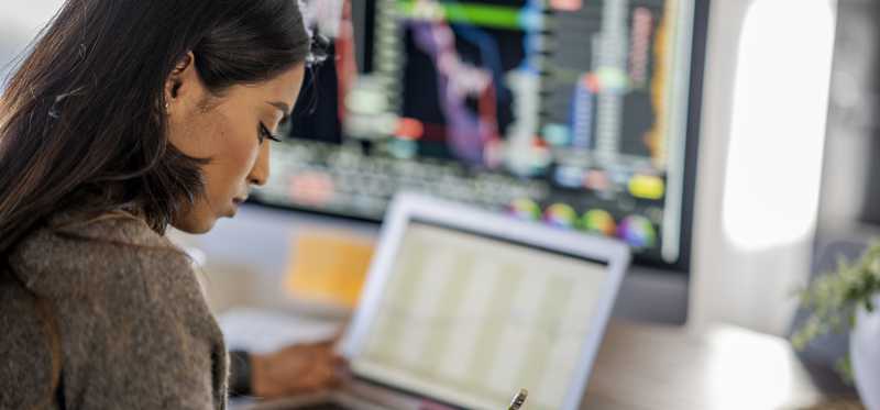 Person reviewing data on multiple computer monitors.