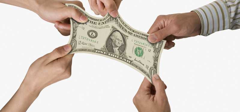 Several hands tugging on dollar bill.