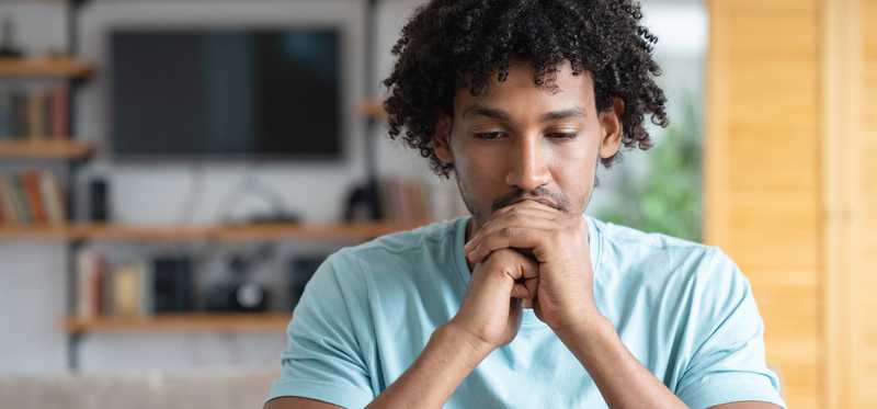 Person sitting pensively at computer looking at the screen.