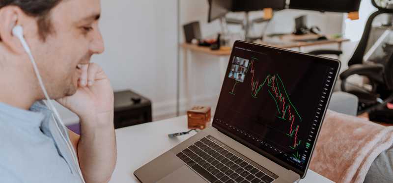 Person on teleconference with stock market chart on laptop screen.