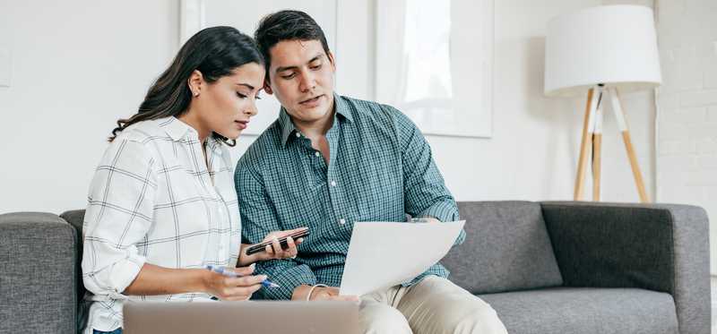 Couple sitting on living room couch and reviewing bank statement