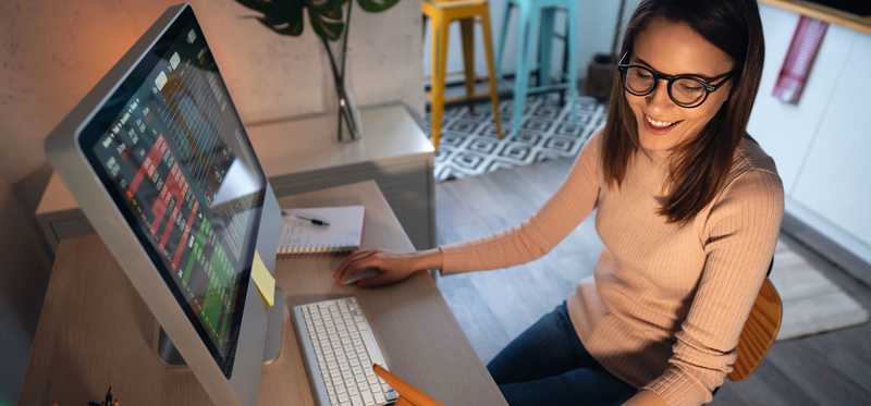 Person in glasses smiling using computer.